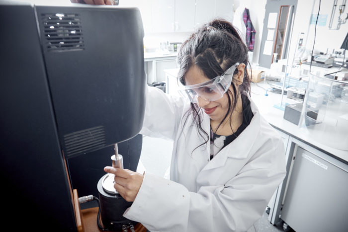 A picture of a Postgraduate Researcher using a piece of machinery with safety glasses on. 